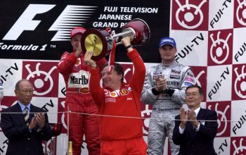 Jean Todt celebrates Rubens Barrichello's victory on the podium at Suzuka